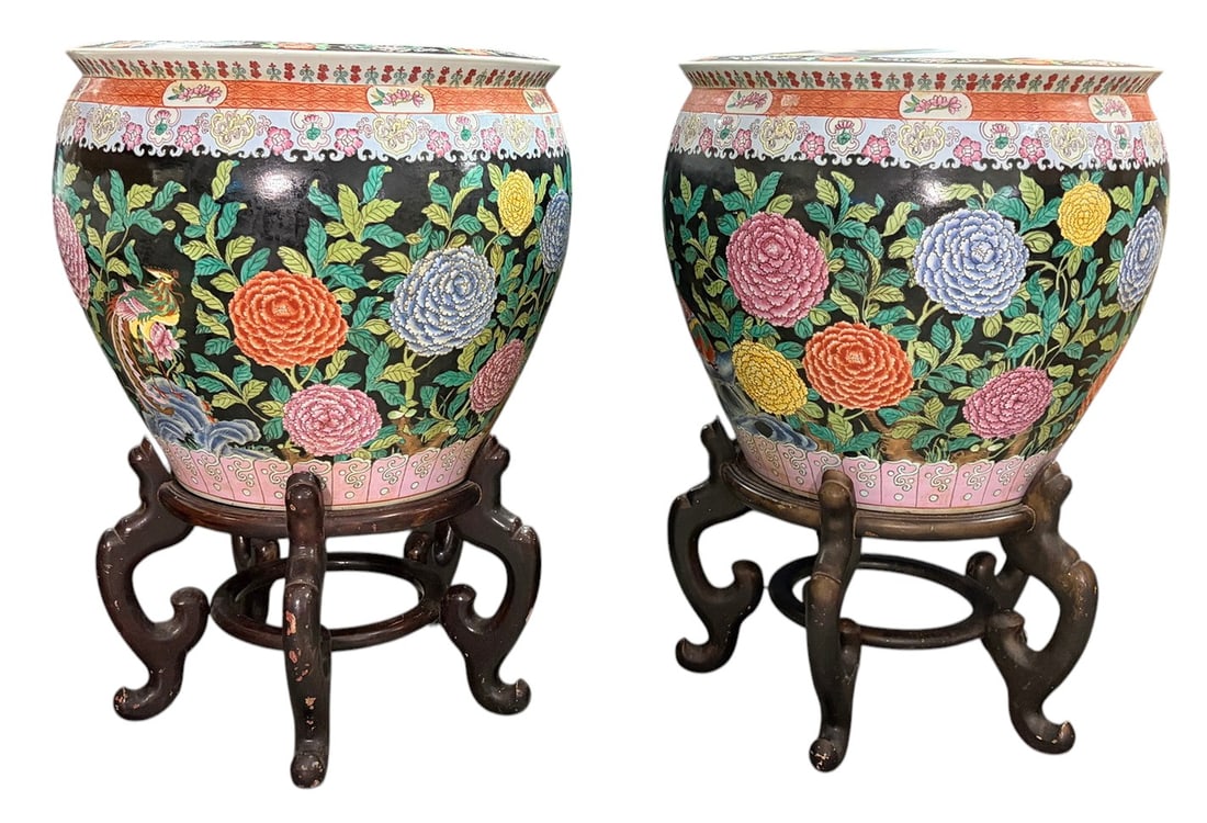 Chinese Pair of Large Porcelain & Wood Planters: Chinese pair of large porcelain jardinieres or planters with polychrome floral decoration on black ground, featuring peonies and foliage with interior fish motif, each raised on carved wood stands. Va
