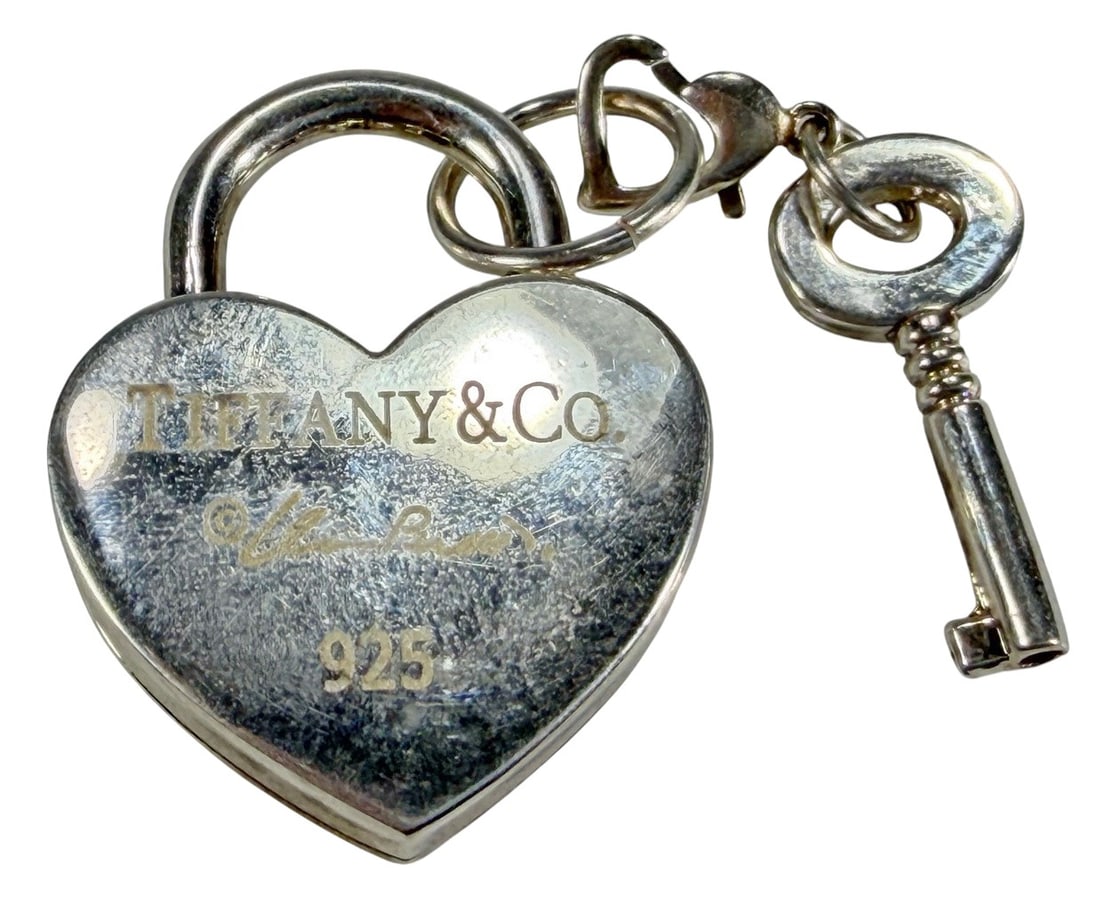 Tiffany & Co Sterling Silver Heart Padlock Pendant: Sterling silver heart-shaped padlock pendant with accompanying key charm. Marked 'Tiffany & Co. 925.' Classic heart lock design associated with the brand. Total weight is 22 grams. Suitable for use as