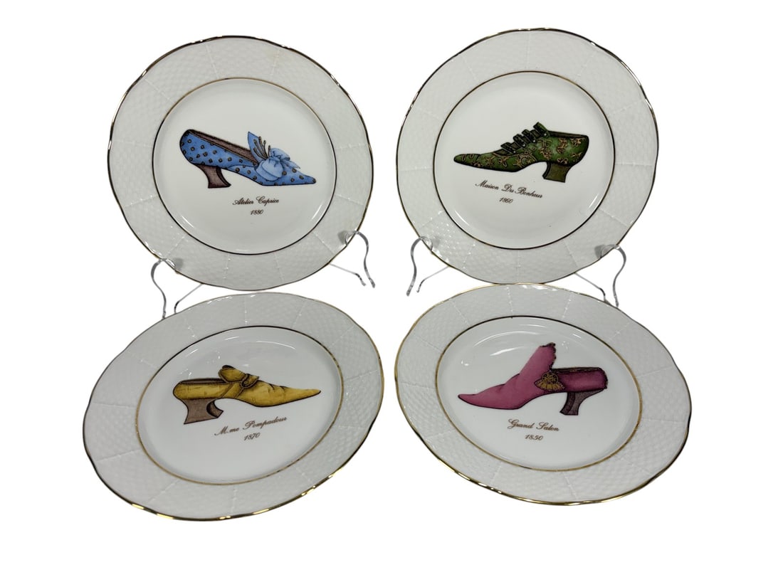 Set Of 4 Godinger Porcelain Plates Limoges France: Set of four Limoges porcelain plates by Godinger, each featuring a central motif of historical footwear with inscribed titles and dates, including examples titled 'Atelier Caprice 1880,' 'Maison du Bo