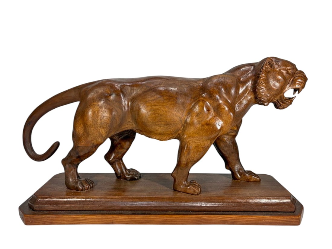 Carved Wood Roaring Panter Sculpture On Base: Carved wood sculpture of a roaring panther, depicted striding forward with open mouth and exposed fangs, mounted on a rectangular tiered base, finished in a warm brown tone highlighting carved