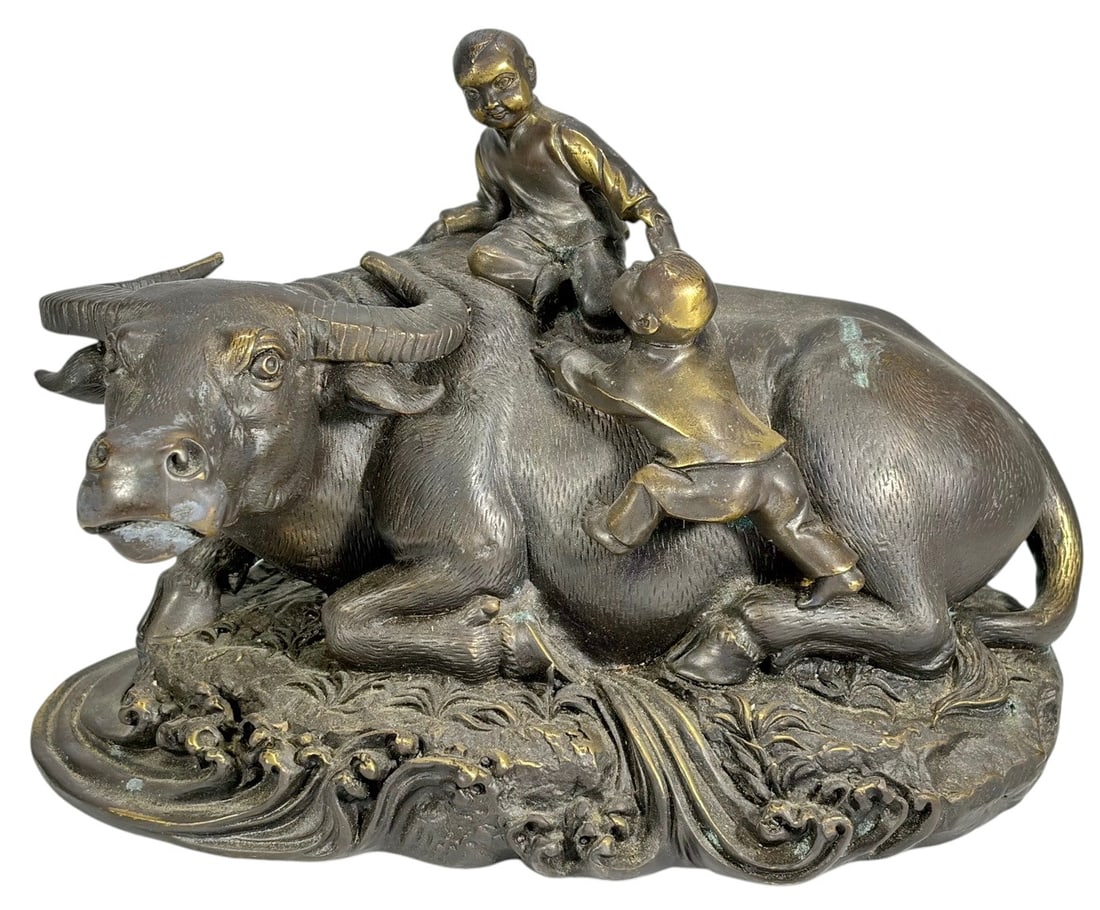 Chinese Bronze Water Buffalo with Boys Sculpture: Cast bronze figural group depicting a recumbent water buffalo with two boys at play, one seated atop the animal and the other climbing along its side, set on an integral naturalistic base with flowing