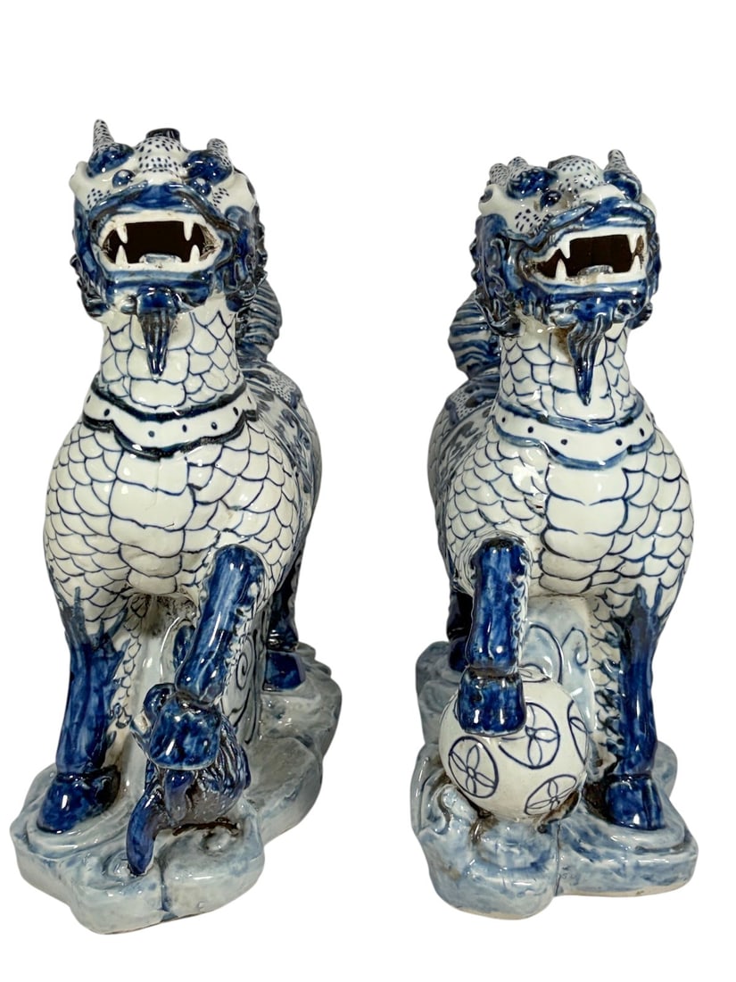 Chinese Glazed Ceramic Foo Dogs Sculptures 2pcs: Pair of Chinese blue and white glazed ceramic foo dogs, each modeled standing on stylized cloud bases, with one resting paw on a brocade ball and the other with a cub, both with open mouths, pronounce