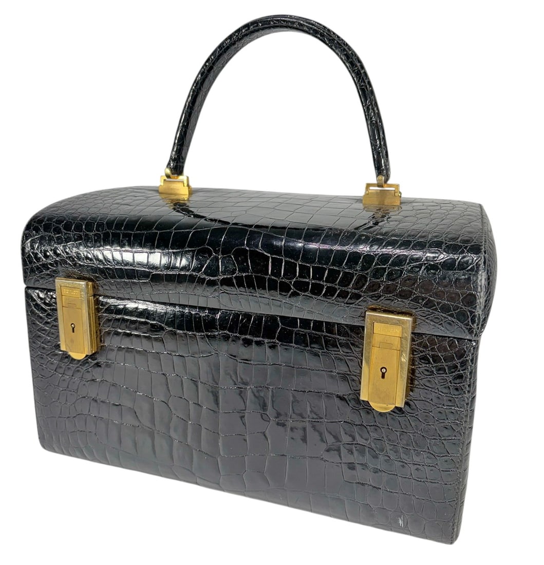 Revlon Italy Black Crocodile Style Train Case: Revlon Italy, black crocodile style leather train case with embossed exterior, structured form with handle and clasps, burgundy lined interior with fitted compartments, marked, Made in Italy. Dimensio