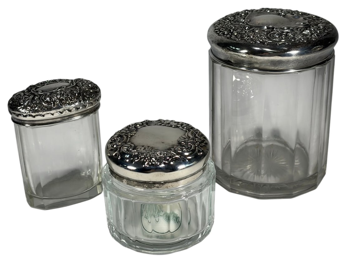 Victorian Silver Plate & Crystal Vanity Jars 3pcs: Victorian style three piece vanity jar set, cut crystal bodies, silver plate lids with repousse floral and scroll motifs, cartouche details, assorted sizes including faceted jar with starburst base, t