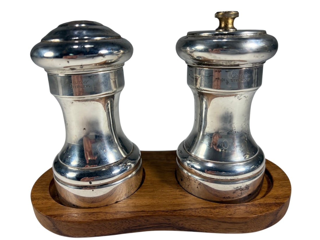 Cartier Sterling Silver Salt-Pepper Shakers 2pcs: Cartier pair of sterling silver salt and pepper shakers, baluster form, pierced pepper top and lidded salt, wooden stand, marked 'Cartier Sterling,' luxury table accessory. Each measures approximately