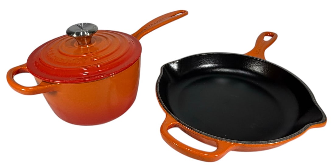 Le Creuset Enameled Cast Iron Cookware 2pc LOT: Le Creuset two piece enameled cast iron cookware set, France, includes skillet with black interior and pour spouts and saucepan with lid and cream interior, orange enamel finish, marked 'Le Creuset Ma