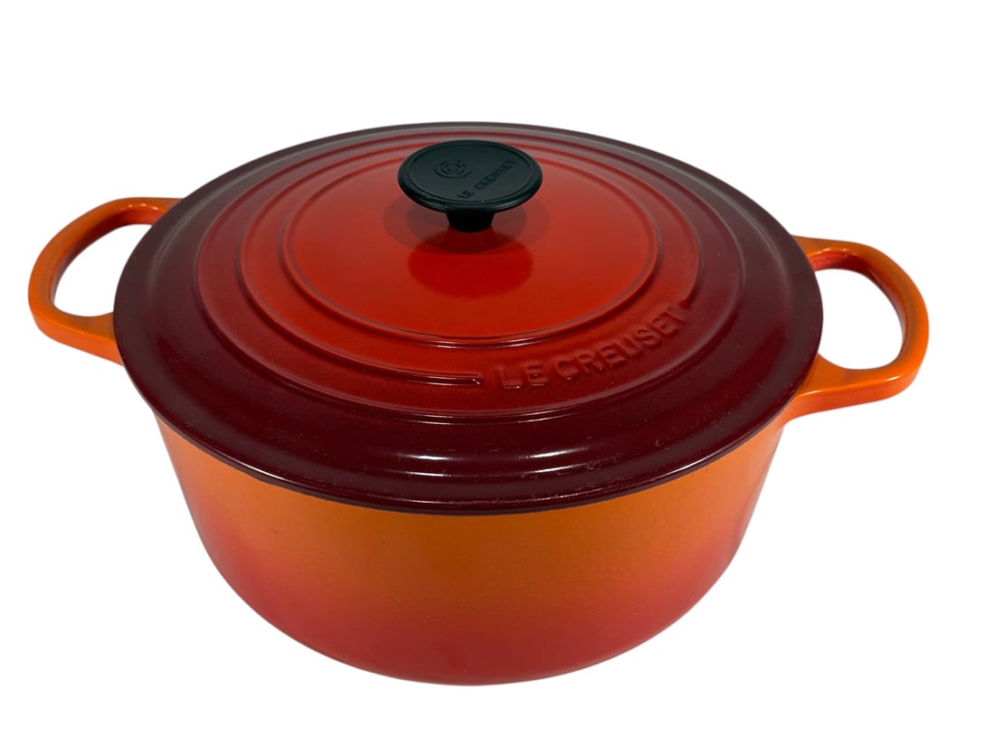 Le Creuset Enameled Cast Iron Dutch Oven w/ Lid: Le Creuset enameled cast iron Dutch oven with lid, round form, orange exterior and cream interior, dual side handles, black knob, marked size 26, 5 1/2 qt, Made in France. Dimensions: 6.5 X 14 X 11 in