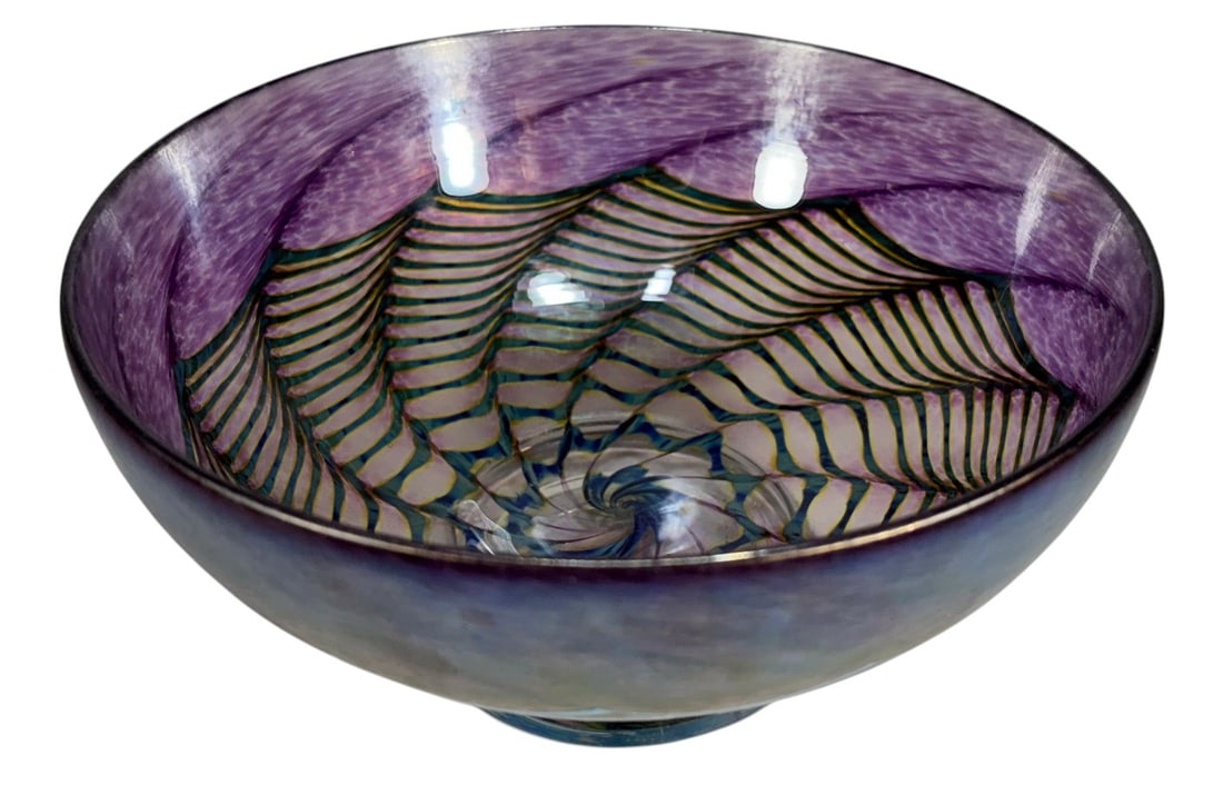 R. Robert Held Purple Spiral Art Glass Bowl: Hand-blown art glass bowl by R. Robert Held Studio, Canada. Purple exterior with iridescent finish and internal spiral pattern in blue and green tones. Raised footed base with multicolor iridescence. 