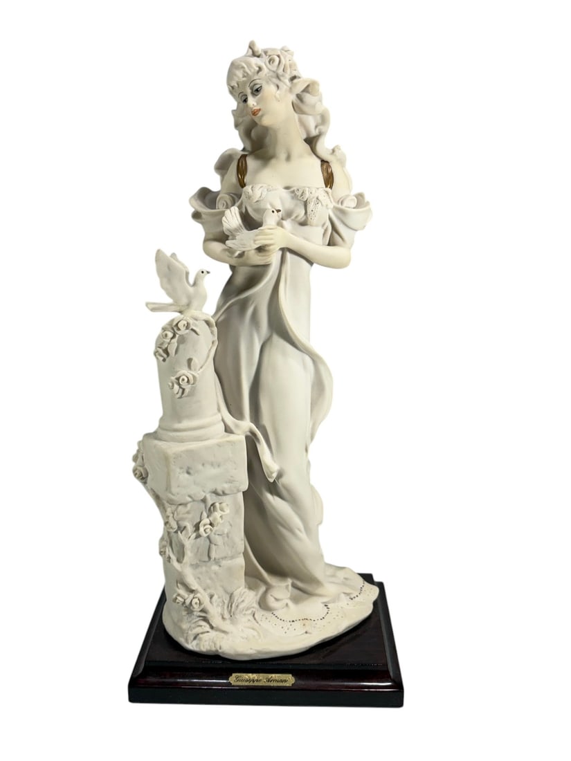 Giuseppe Armani Lady w/ Doves Figurine 1987: Figurine by Giuseppe Armani depicting a lady holding doves, raised on an integrated base with a bird perched on a column. Mounted on a wooden plinth with a brass nameplate reading 'Giuseppe Armani.' T