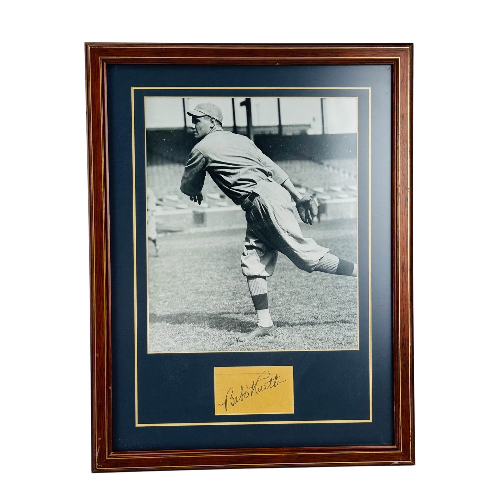 Babe Ruth Autographed Black White Baseball Photo: Babe Ruth autogtaphed cut signature presented with a black and white photograph. Depicts the baseball player in uniform during play. Signature mounted alongside the image within a double matted