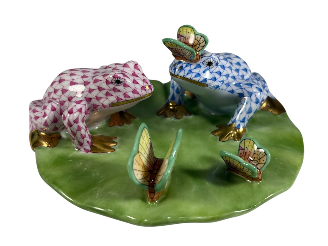 Herend Frogs on Lily Pad Porcelain Figure 5926: Herend hand-painted Hungarian porcelain figural group model 5926, depicting two frogs on a lily pad with three butterfly accents. Decorated in Herends signature fishnet pattern in raspberry and blue