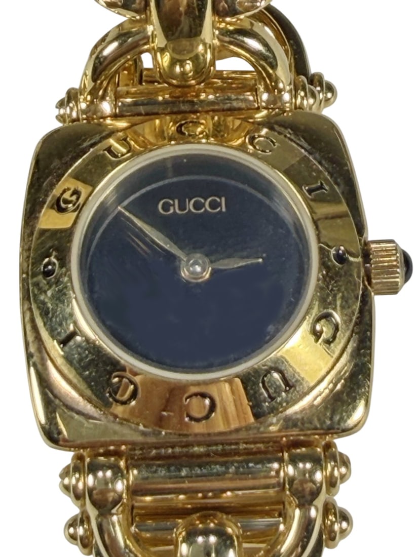 Gucci 6400L Gold Tone Horsebit Chain Wristwatch: Ladies Gucci 6400L Swiss made quartz wristwatch with gold tone stainless steel case measuring approximately 26 x 26 mm and signature horsebit chain bracelet. Features black dial with Gucci logo bezel,