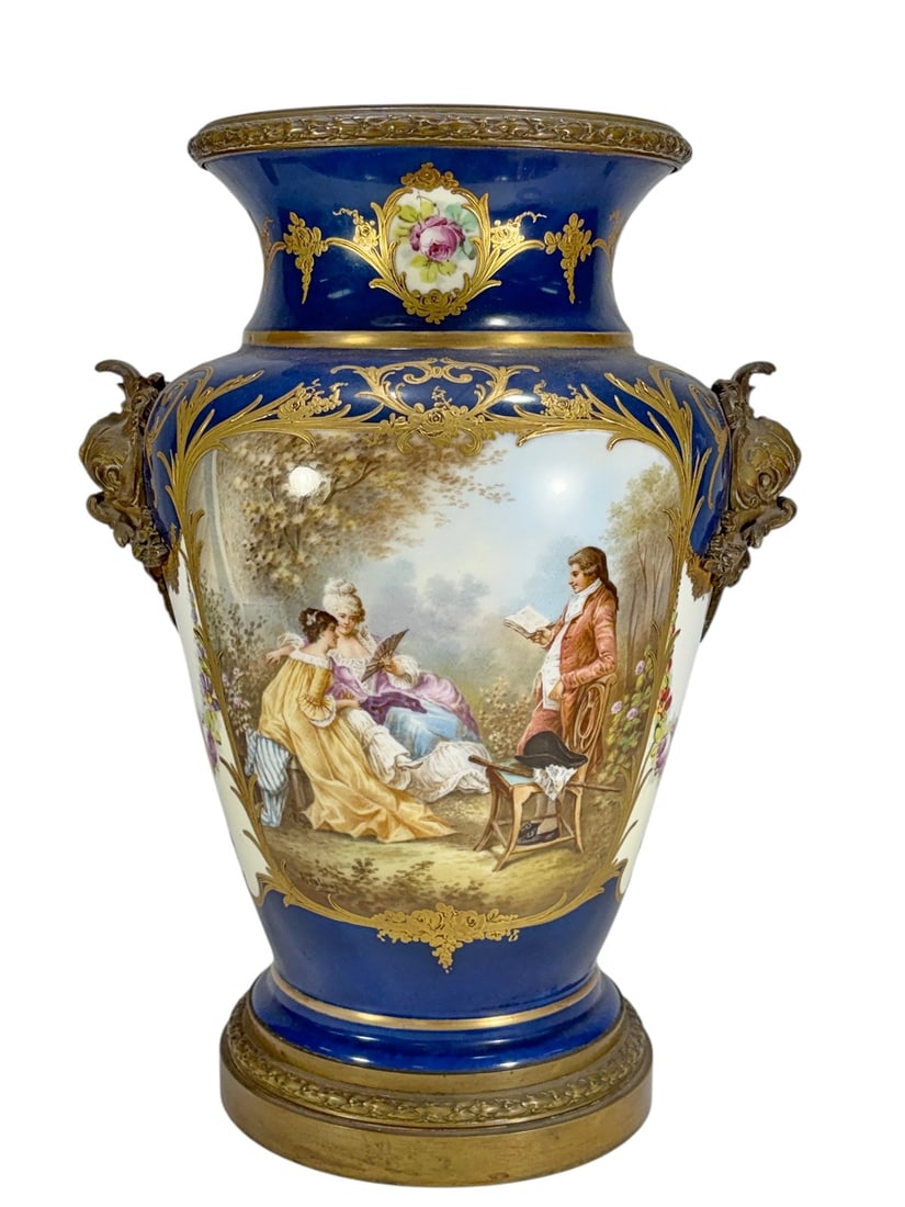 Large Sevres Porcelain Bronze Mounted Urn Vase: Large cobalt blue porcelain vase featuring hand-painted romantic and landscape scenes with floral reserves and extensive gilt decoration throughout. Mounted with ornate bronze tone figural handles