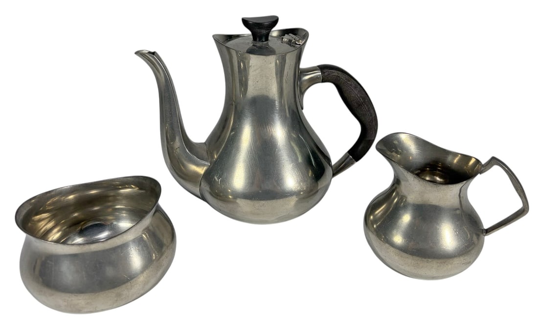 Don Pewter England Coffee/Tea Service 3pc LOT: Three-piece Don Pewter coffee or tea service comprising a coffeepot, creamer, and covered sugar bowl in modernist pewter form with dark handles and finial details. Marked Don Pewter, Made in