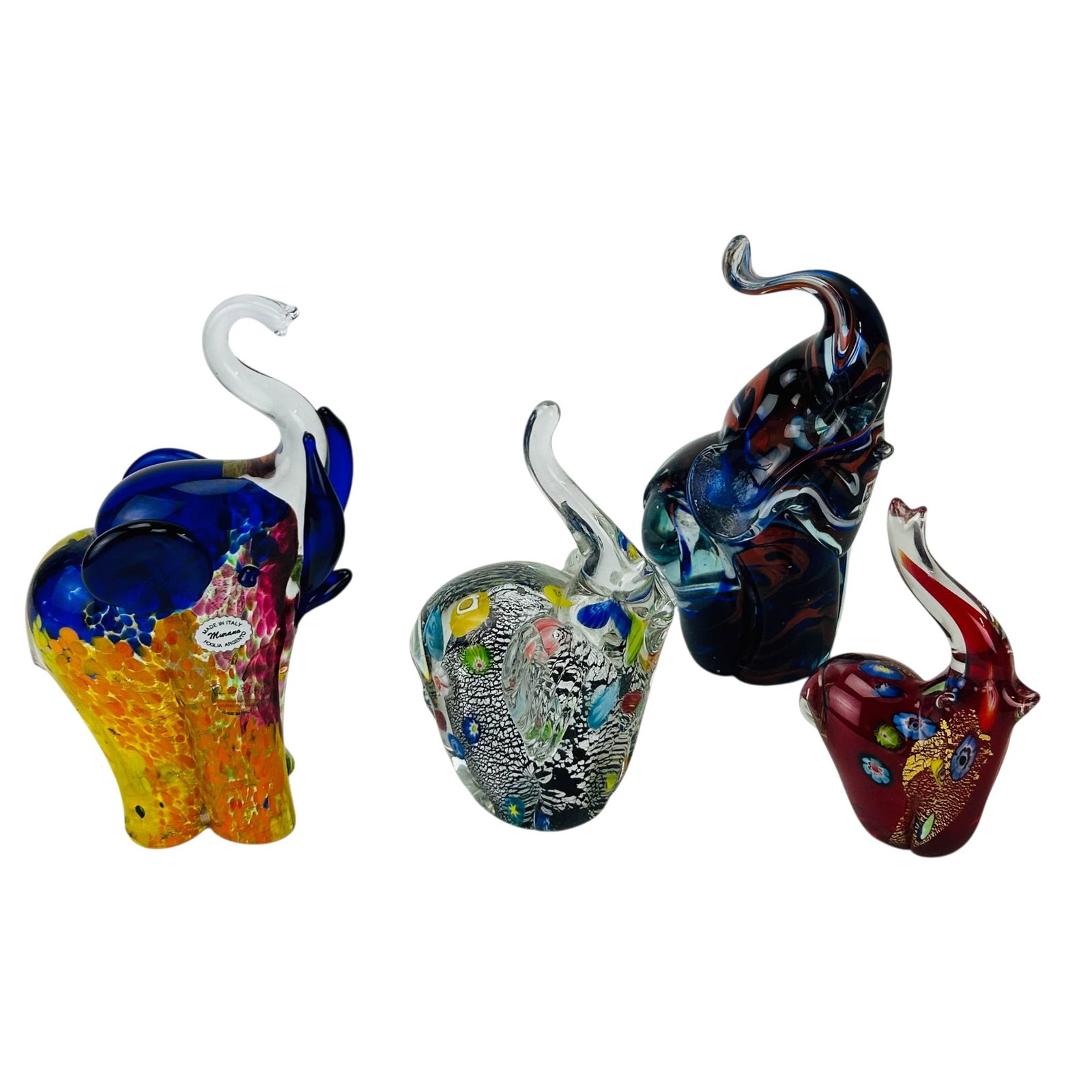 Murano & Mdina Glass Elephant Sculpture 4pc SIGNED: Group of four studio hand blown art glass elephant figurines modeled with raised trunks. Includes a Murano example labeled Vetreria Artistica Murano Foglia Argento with engraved signature and encased 
