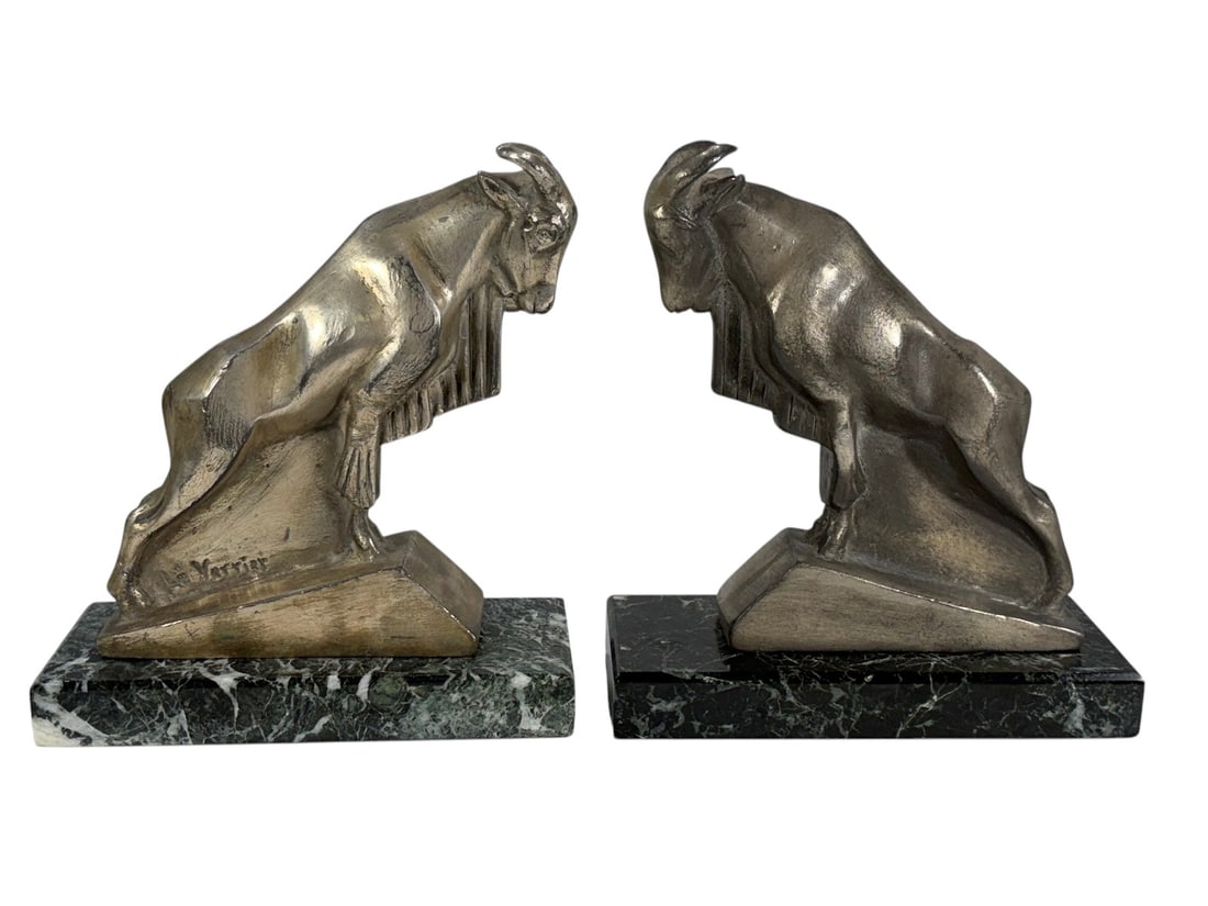 Pair of Max Le Verrier Style Bronze Goat Bookends: Pair of silver tone bronze figural goat bookends in the style of Max Le Verrier, each depicting a stylized mountain goat in profile on stepped plinth. Mounted on green Italian marble bases. Art Deco s