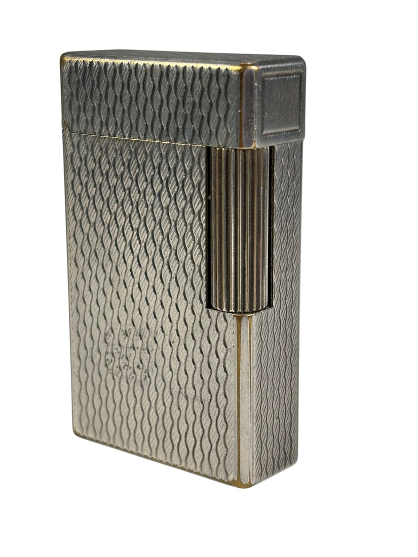 S.T. Dupont France Ligne 1 Silver Plated Lighter: S.T. Dupont Ligne 1 silver plated lighter with engine-turned pattern. Marked S.T. Dupont de Paris, Made in France. Serial number present to base. Dimensions: 2.25 X 1.5 X 0.5 in. Condition: Good ov