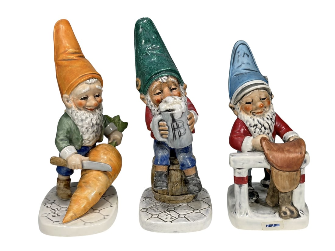 Assorted Goebel Germany Co-Boy Gnome Figurines 3pc: Group of three Goebel Co-Boy porcelain gnome figurines from the whimsical Co-Boy series. Includes a seated gnome holding a money bag, a gnome working at a cobblers bench identified as Herbie, and a ga