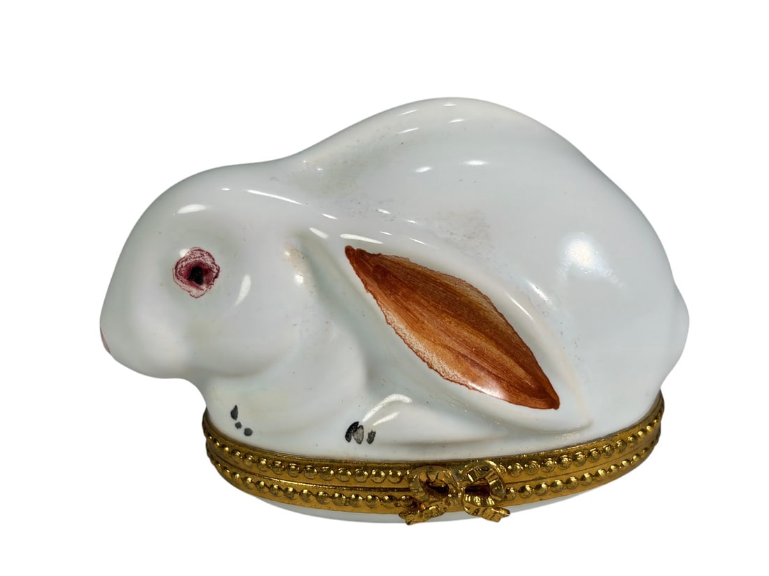Rochard Limoges Rabbit Porcelain Trinket Box: Hand-painted Rochard Limoges porcelain trinket box modeled as a resting white rabbit with pink eye and brown-highlighted ear. The box features a gilt metal hinged mount with decorative clasp and hand-