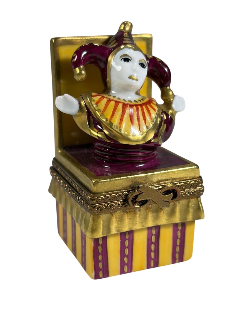 Limoges Porcelain Jack-in-the-Box Trinket Box Art: Hand-painted Limoges porcelain trinket box modeled as a colorful jack-in-the-box toy. The box features yellow and burgundy striped decoration with gilt accents and a three-dimensional jester figure em