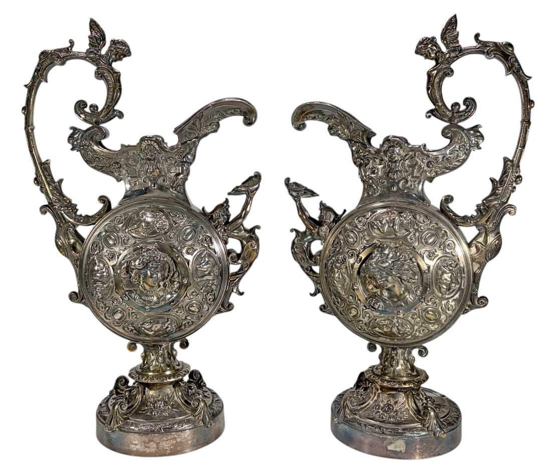 Pair Renaissance Revival Bronze Figural Ewers Vase: Pair of highly ornate Renaissance Revival bronze figural ewers or decorative vases with silvered finish and traces of gilt highlights. Each vessel features extensive relief decoration with classical f