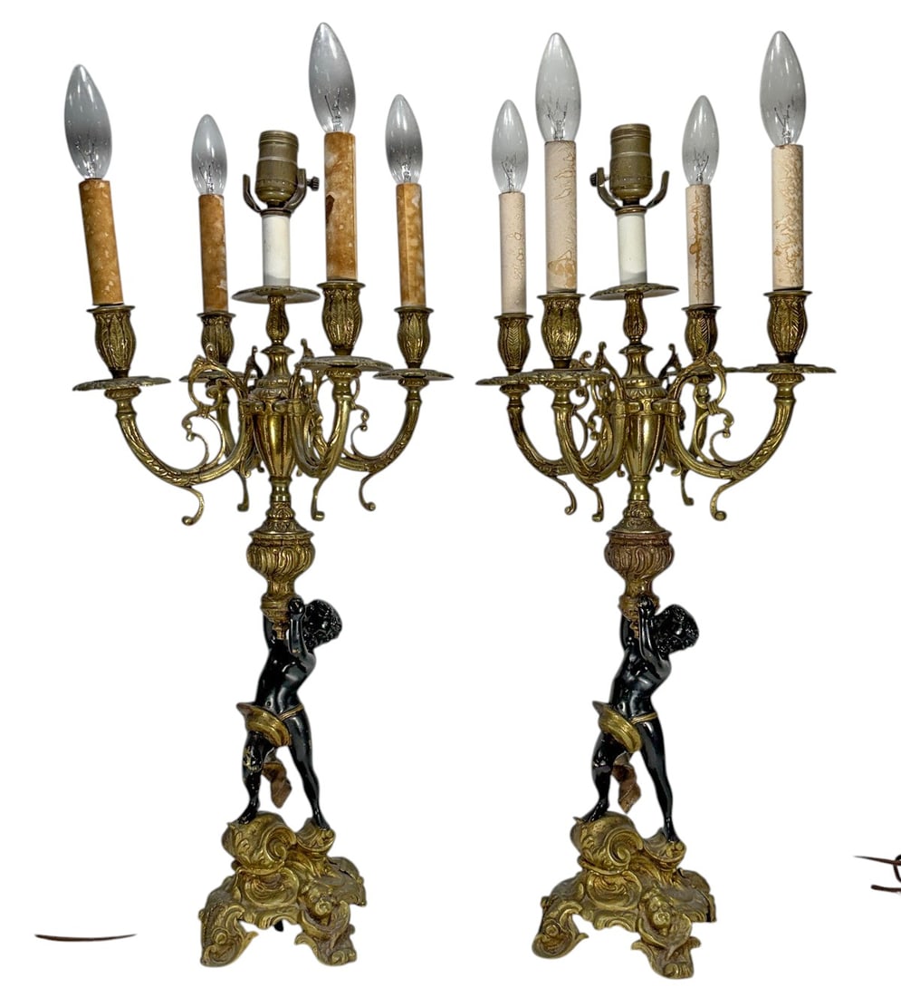 Figural Cherub Bronze Five Light Candelabras 2pcs: Pair of figural five-light candelabra table lamps in bronze with gilt finish. Each features a standing cherub figure supporting a scrolling five-arm candelabra with decorative foliate and acanthus mot