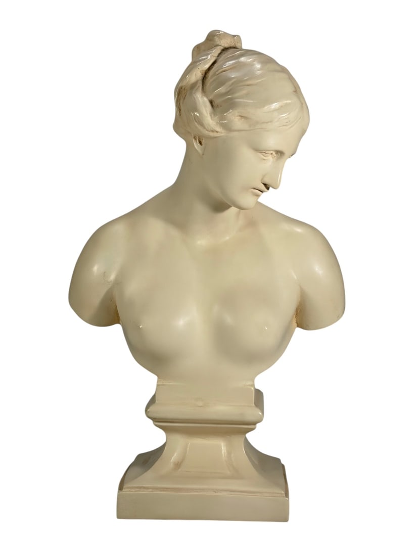 Classical Female Resin Bust Sculpture on Pedestal: Decorative resin sculpture of a classical female bust with lowered gaze, swept-back hair, and an ivory-toned faux marble finish. Inspired by Neoclassical sculpture and mounted on a stepped pedestal ba