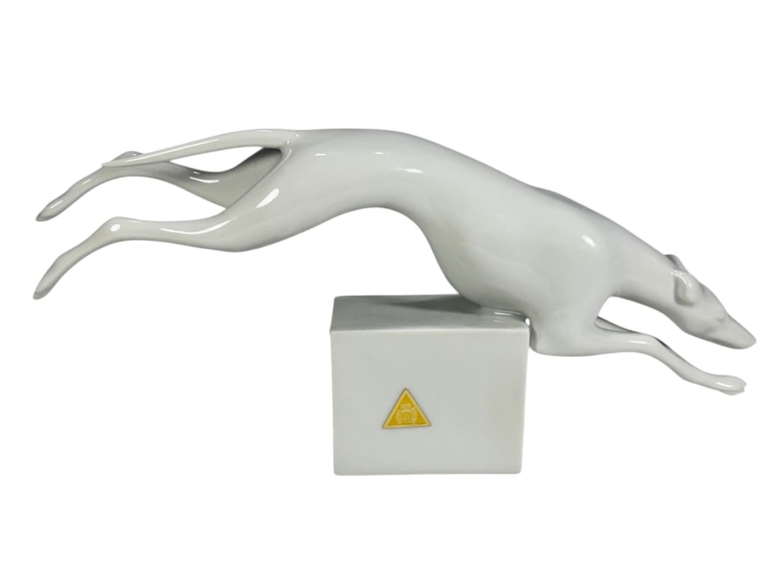 Royal Dux Porcelain Greyhound Sculpture Figurine: Vintage Royal Dux porcelain sculpture depicting a leaping greyhound or whippet on a rectangular plinth base. Executed in glossy white porcelain with Art Deco styling. Marked with the Royal Dux pink tr