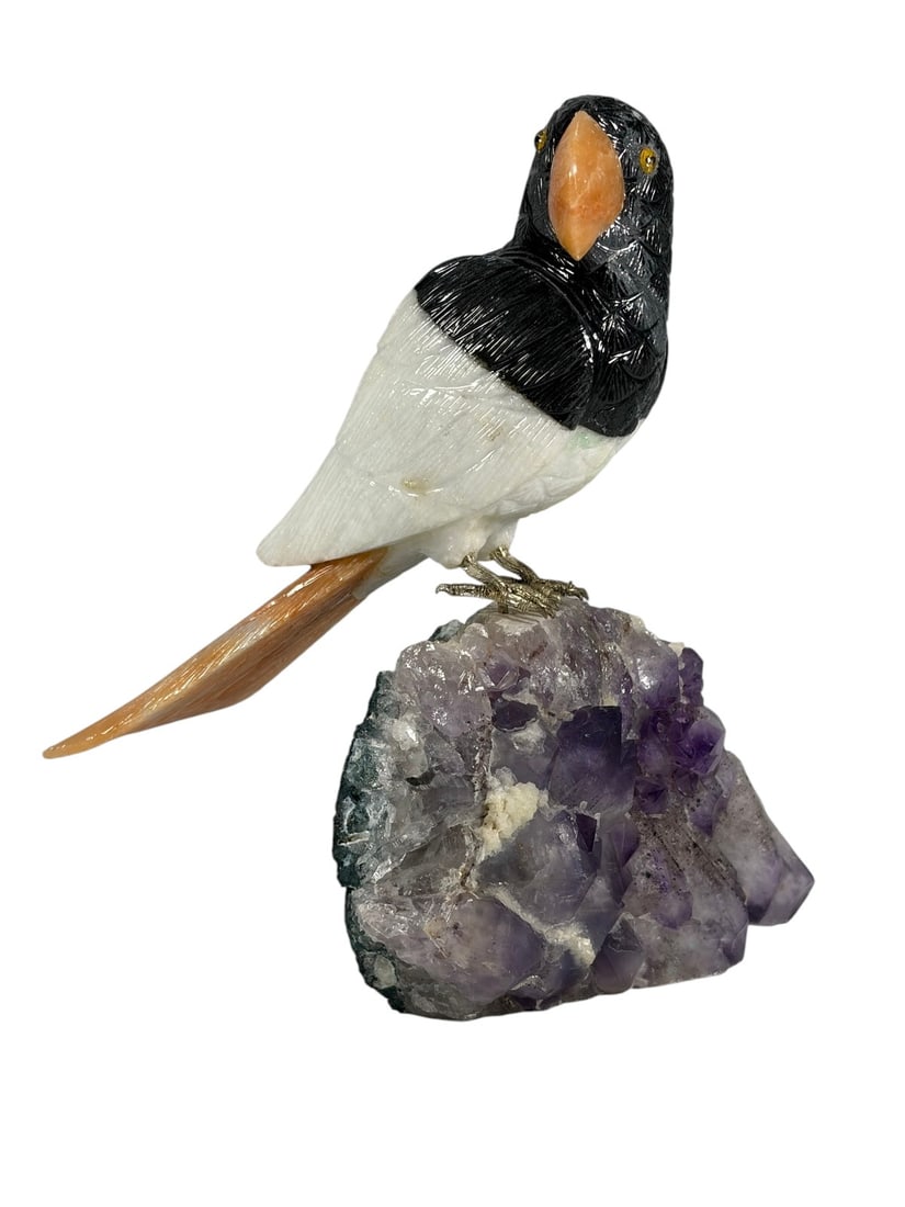 Carved Hardstone Bird on Amethyst Crystal Base: Carved hardstone bird sculpture with black, white, and orange stone body, inset eyes, and metal legs. The bird is mounted on a natural amethyst crystal cluster with green matrix stone. Executed in mul