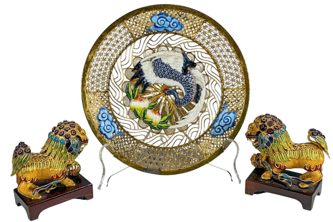 Chinese Cloisonne Metal Dish & Foo Dog Figures 3pc: Group comprising a Chinese cloisonne enamel dish and a pair of cloisonne guardian lion figures on wooden stands. The dish features an openwork crane and peach design with cloud motifs, while the figur