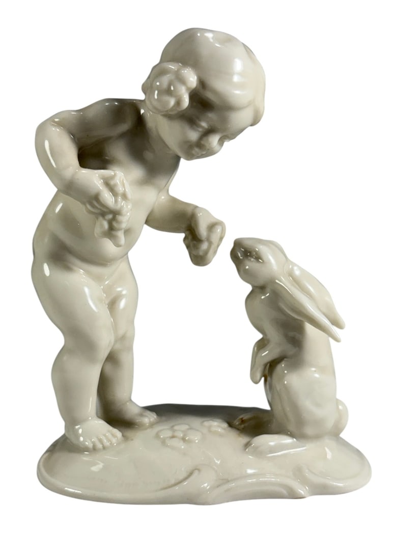 Hutschenreuther Child Feeding Rabbit Figurine Art: Vintage Hutschenreuther Selb Kunstabteilung porcelain figurine depicting a child feeding a rabbit. Executed in glossy white porcelain with floral decorated base. Retains original factory and retailer 
