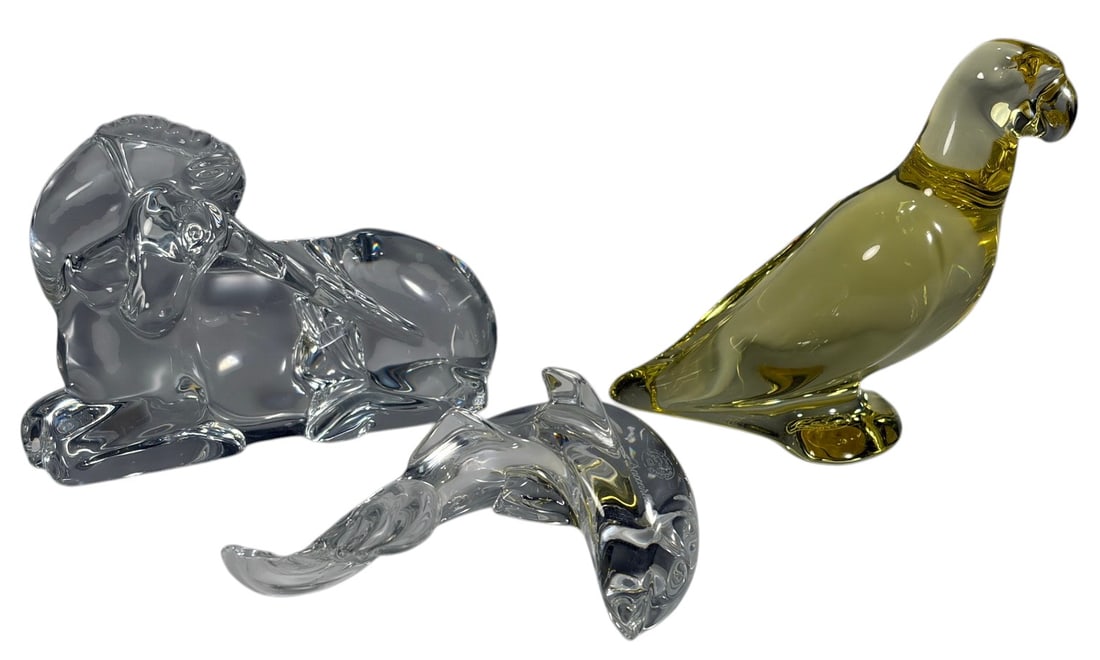Baccarat France Crystal Animal Figurines 3pc LOT: Group of three Baccarat crystal animal figurines comprising a yellow-tinted parrot, a clear reclining ram with curled horns, and a clear dolphin or fish with sweeping tail. Each sculpture is crafted i