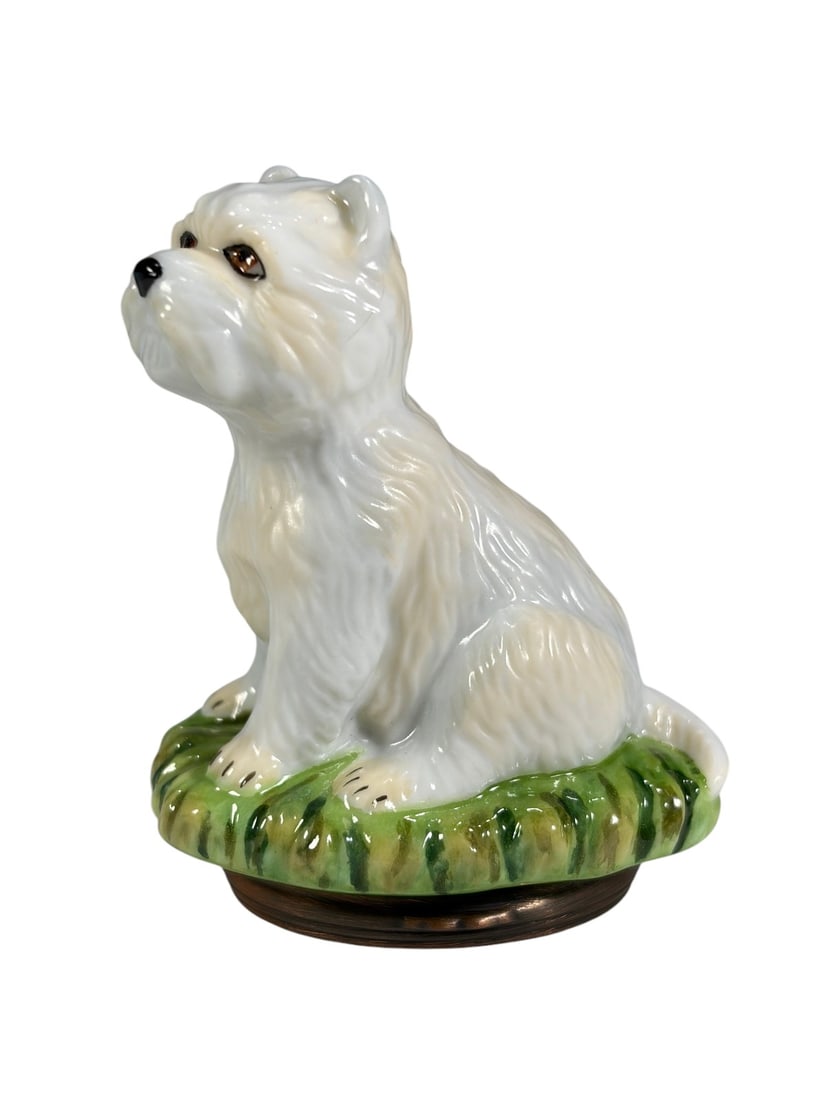 Halcyon Days West Highland Terrier Enamel Box: Halcyon Days enamel trinket box in the form of a seated West Highland Terrier standing on a green grassy base. The hinged box opens to reveal a hand-painted interior featuring a dog bowl and bone moti