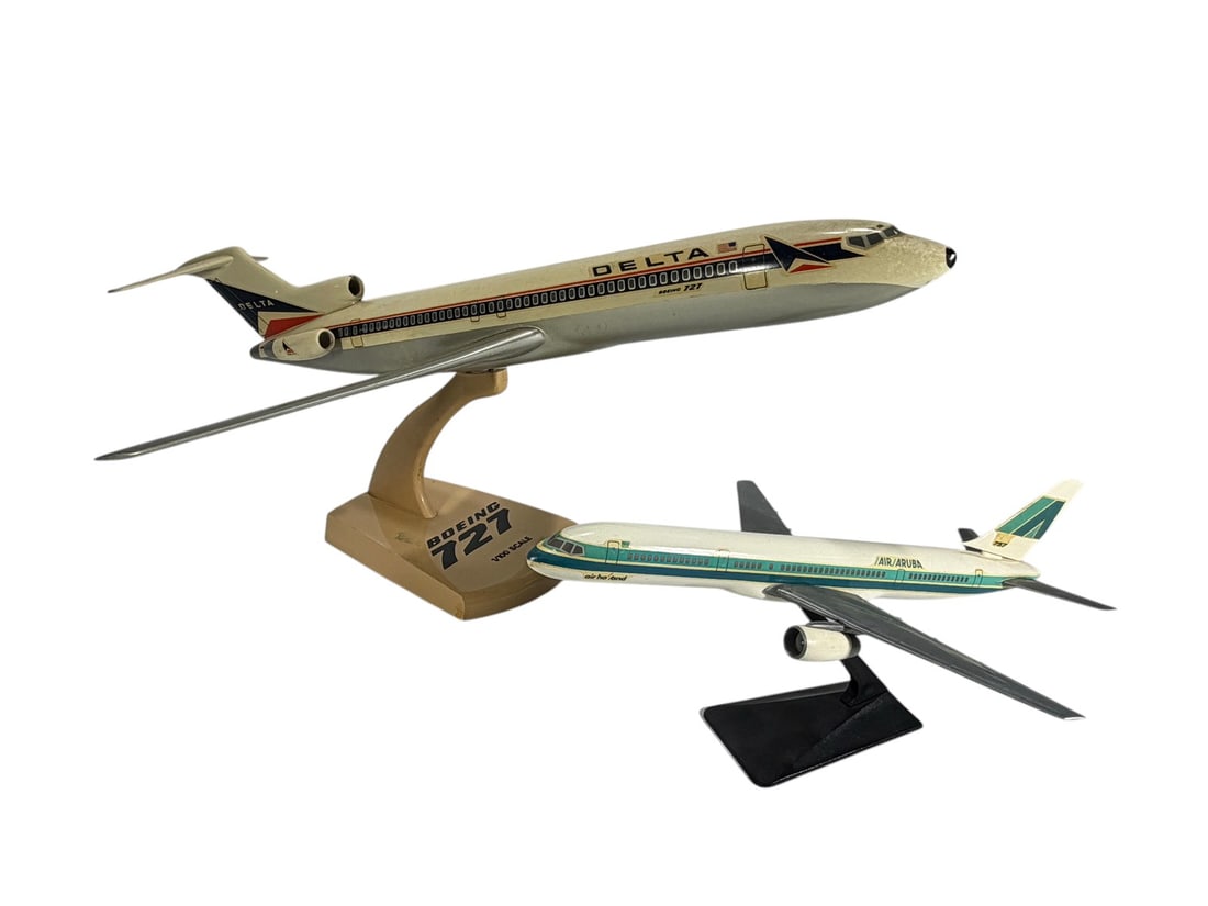Die-Cast Airline Model Commercial Airplanes 2pcs: Lot of two display model commercial airliners on stands. Includes a Delta Air Lines Boeing 727 model marked "1/100 Scale" on the display base and an Air Aruba jetliner model in the carrier's teal and 
