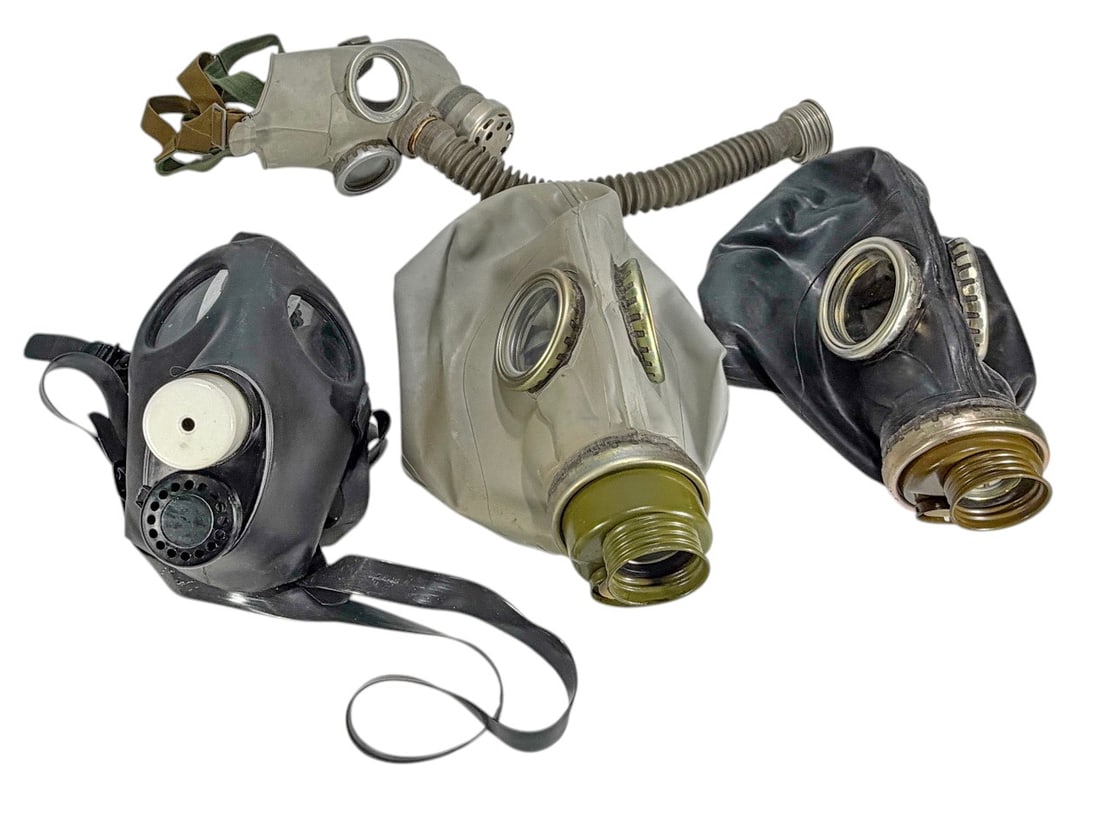 Assorted Military Surplus Gas Masks & Hose 4pc LOT: Lot of four military surplus gas masks in assorted styles and colors, including gray and black rubber examples with glass eye lenses. The group includes one mask with attached corrugated breathing hos