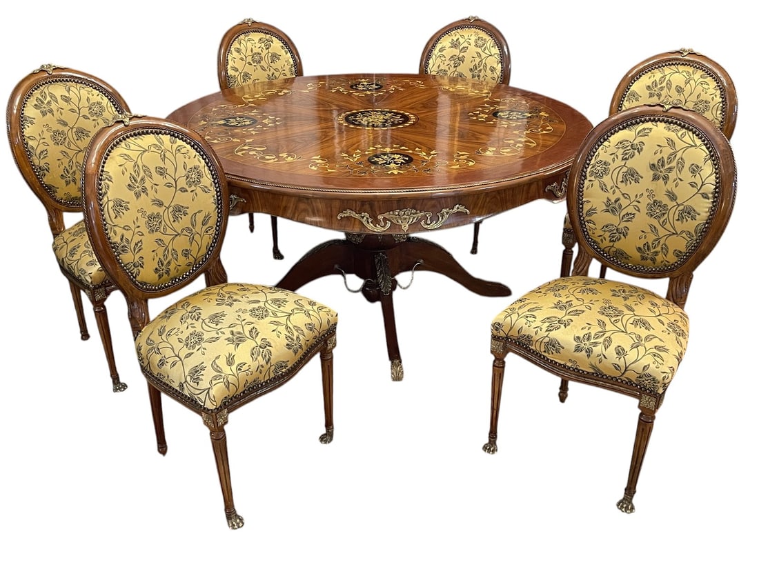 French Marquetry Bronze Mounted Round Dining Table: French style round dining table crafted in wood with elaborate marquetry decoration executed in contrasting wood veneers. The circular top features a radiating veneer pattern centered by a floral marq