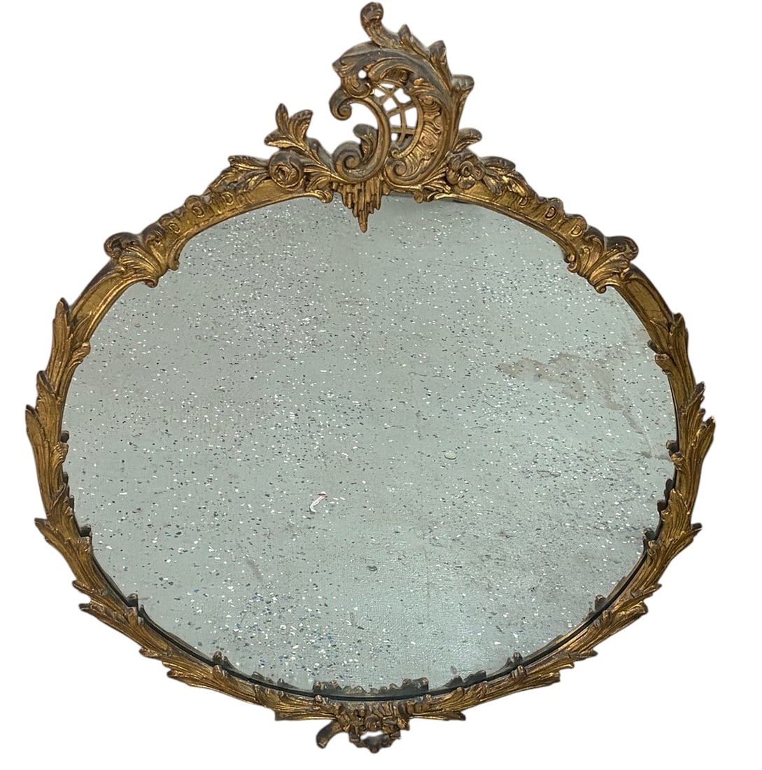 French Style Giltwood Round Wall Mirror Frame: Decorative French style round wall mirror with an elaborately molded giltwood frame featuring scrolling foliate motifs, floral accents, and an ornate pierced crest. The circular frame is finished in a