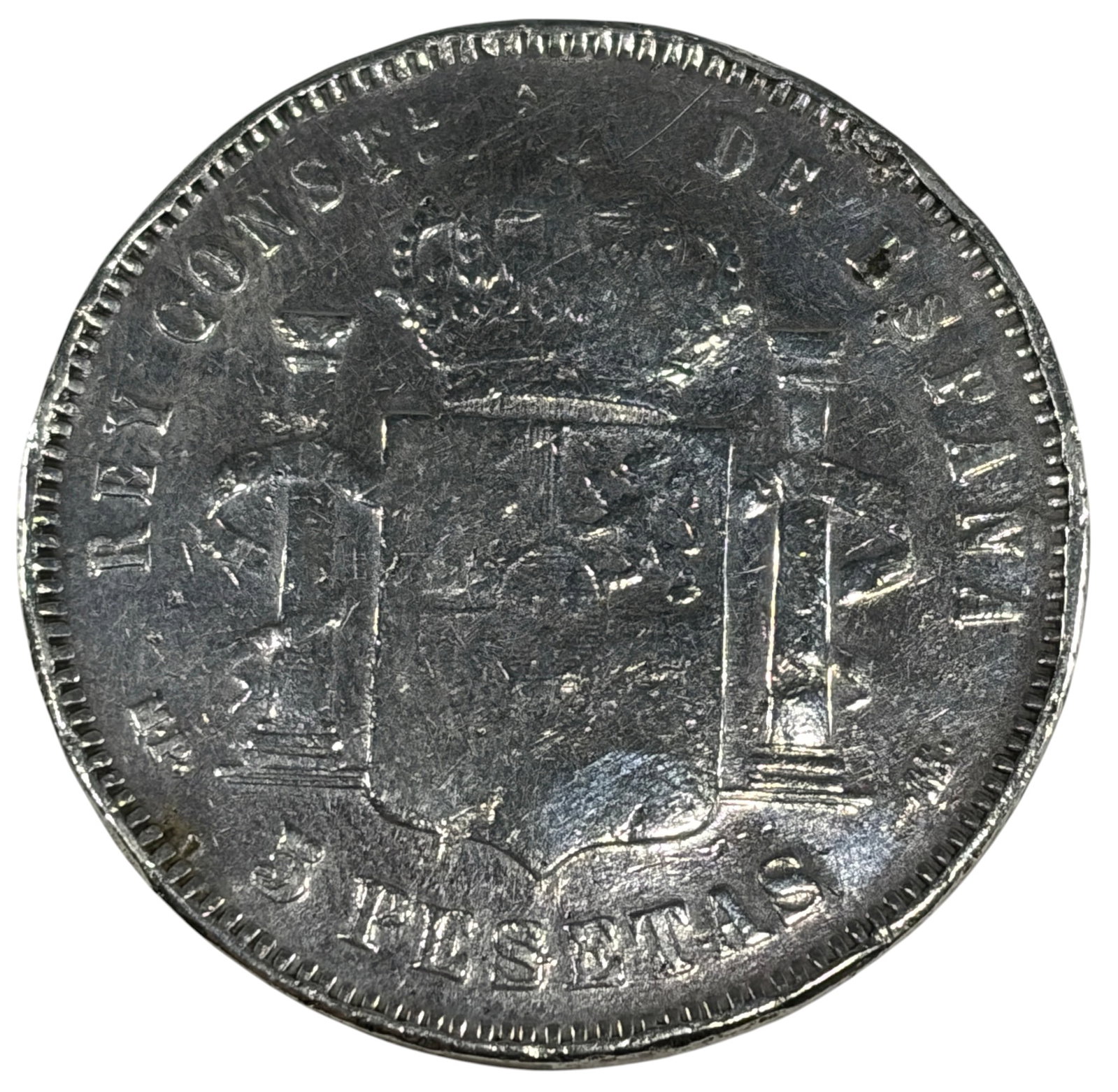 1885 Spain 5 Pesetas King Alfonso XII Silver Coin: 1885 Spain 5 Pesetas silver coin featuring a left-facing portrait of King Alfonso XII on the obverse and the crowned Spanish coat of arms between the Pillars of Hercules on the reverse. Dated 1885. St