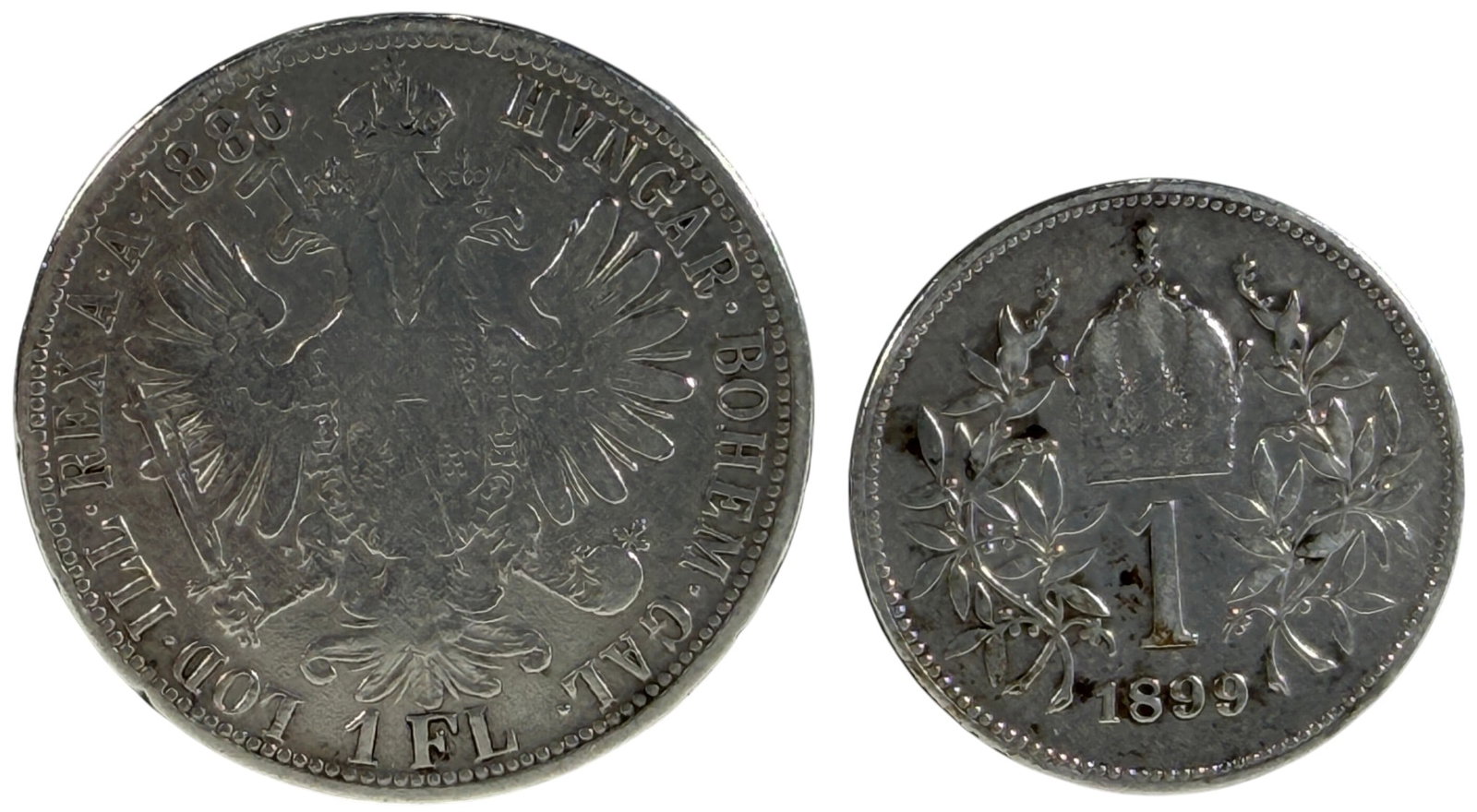 1886-1899 Austria Florin & Corona Silver Coins 2pc: Lot of 2 Austrian silver coins from the reign of Emperor Franz Joseph I.1886 1 Florin (1 FL) - .900 silver, 12.34 grams, 30 mm diameter.1899 1 Corona (1 Krone) - .835 silver, 5 grams, 23 mm diameter.B