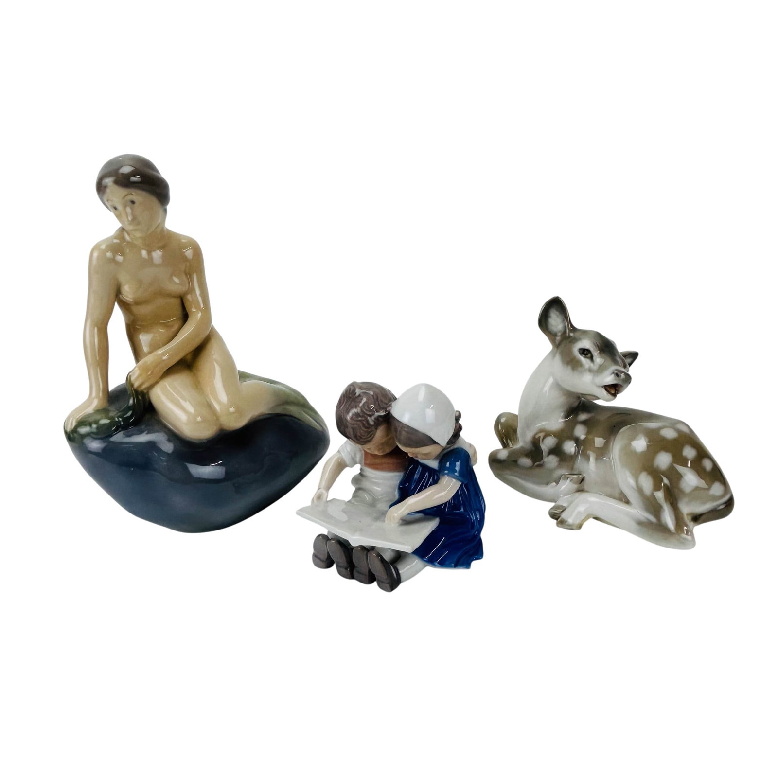 Royal Copenhagen and Bing Grondahl Figurine LOT 3p: Group of three Scandinavian origin porcelain figures. Includes a Royal Copenhagen Denmark Fawn Lying Down #2609 and Little Mermaid #4431 along with a Bing and Grondahl figurine # 1567 titled Children 