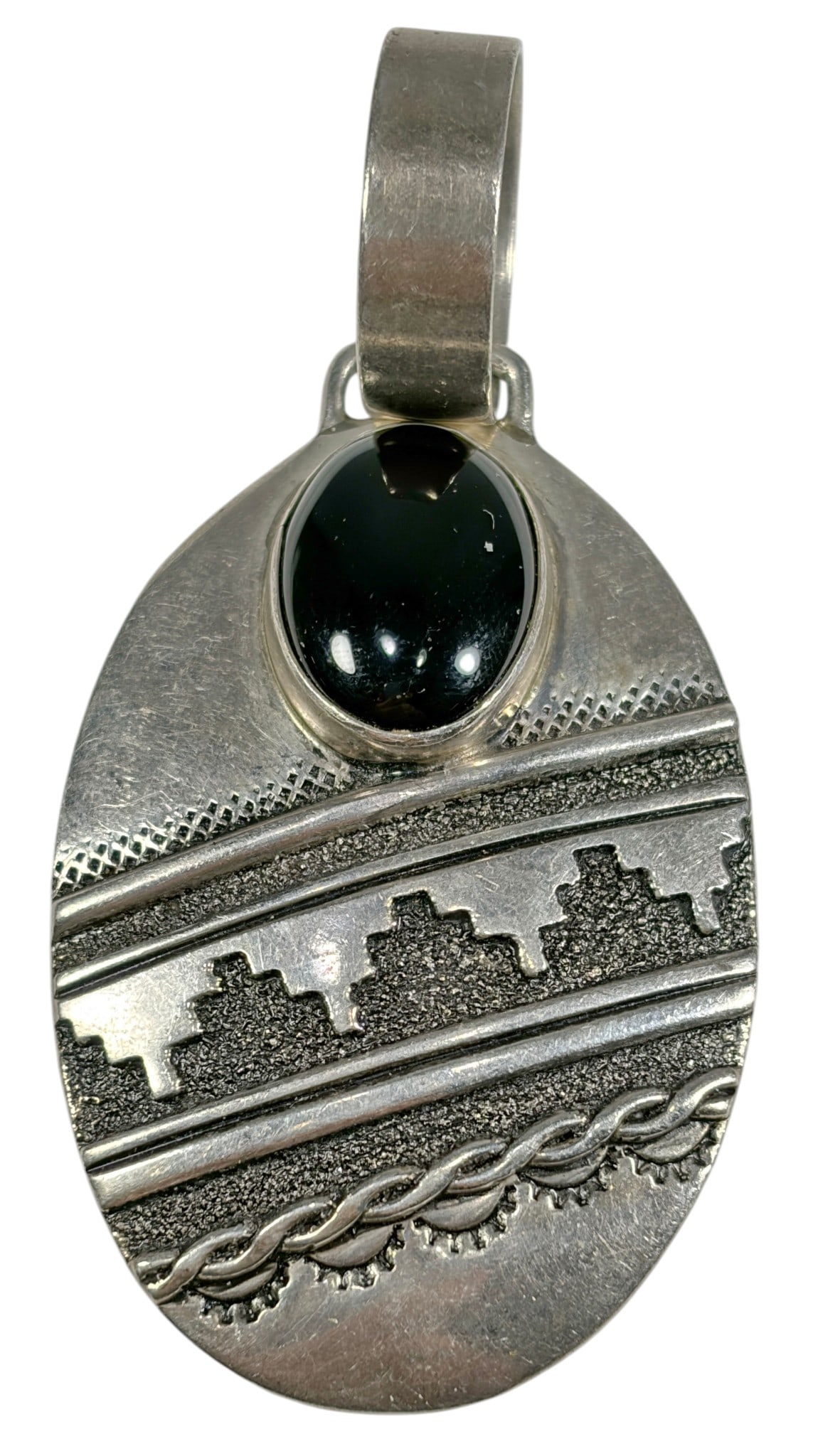 Sterling Silver Onyx Southwestern Pendant 27.1: Sterling silver oval pendant featuring a polished oval black onyx cabochon above engraved Southwestern geometric and rope-style designs. The pendant has a large integrated bail and a smooth polished r