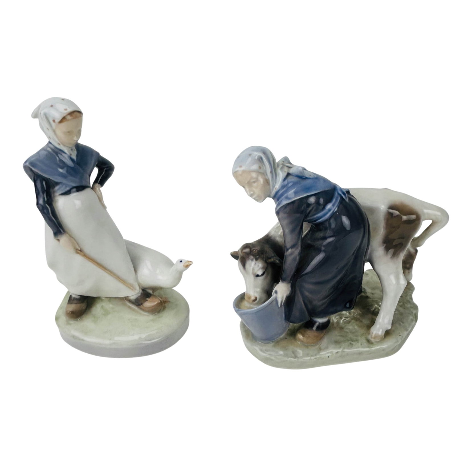 Royal Copenhagen Danish Porcelain Genre Figurines: Royal Copenhagen Denmark porcelain figural groups, comprising a young girl herding a goose and a milkmaid feeding a calf from a bucket. Both figures are modeled in traditional Danish rural dress with 