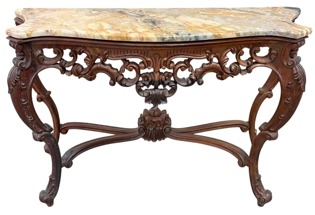 French Rococo Marble Top Console Table Carved Wood: French Rococo style console table featuring an elaborately carved walnut-finished wood base with scrolling acanthus, floral, and shell motifs. The shaped variegated marble top displays cream, gold, gr