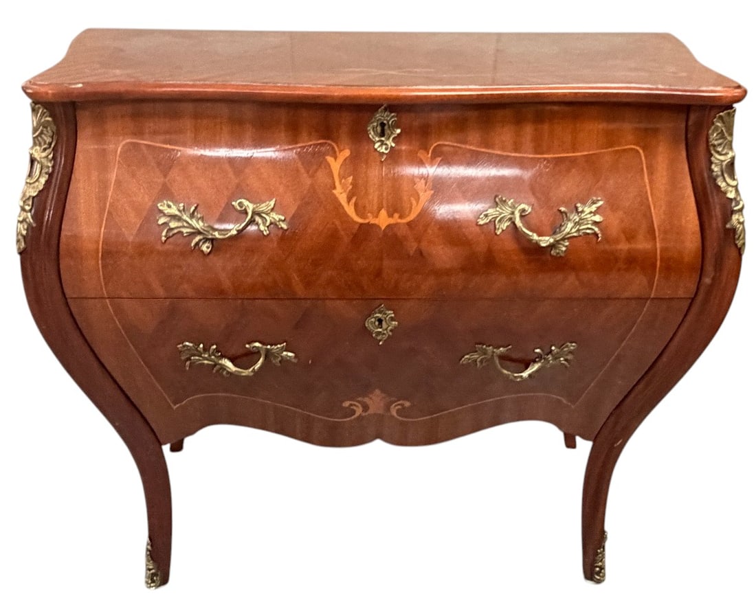 French Louis XV Style Bombe Chest Mahogany Inlay: French Louis XV style bombe chest featuring a shaped top, two dovetailed drawers, and fine mahogany veneer with geometric and floral marquetry inlay. Accented with ornate gilt bronze mounts, escutcheo