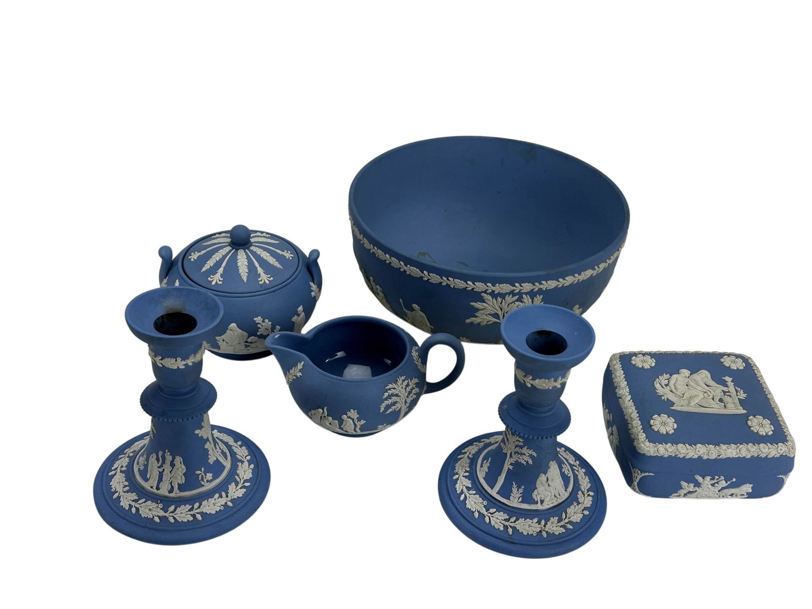 Wedgwood Bowl Box Creamer Sugar Candleholders LOT: Collection of five Wedgwood English Blue Jasperware pieces including a covered sugar bowl, a milk creamer, square trinket box with lid, pair of candlesticks and a large serving bowl. Each displays app