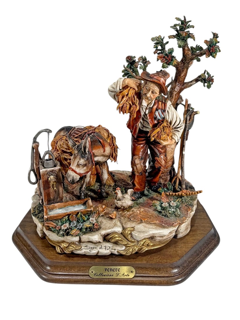 Venere Italian Figurative Sculpture On Wood Base: Italian polychrome figurative sculpture from the Venere Collezione D'Arte collection depicting a farmer carrying harvested sheaves beside a donkey, chickens, a well, and a tree. Mounted on a shaped wo