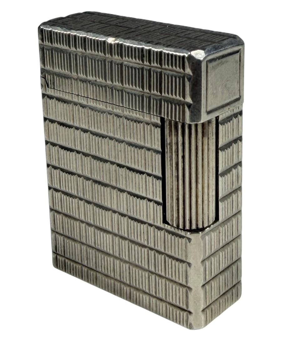 S.T. Dupont Ligne 1 Silver Tone Lighter France: S.T. Dupont Ligne 1 silver-tone butane lighter, made in France. Features an allover vertically engraved geometric pattern with the classic rectangular form and hinged lid. The underside is marked "S.T