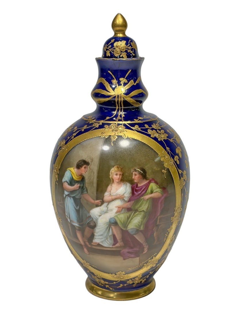 19 Century Old Vienna Cobalt Porcelain Covered Urn: Old Vienna cobalt blue porcelain covered urn vase featuring a hand-painted oval reserve depicting a classical figural scene, framed by elaborate gilt floral and ribbon decoration. The reverse is decor
