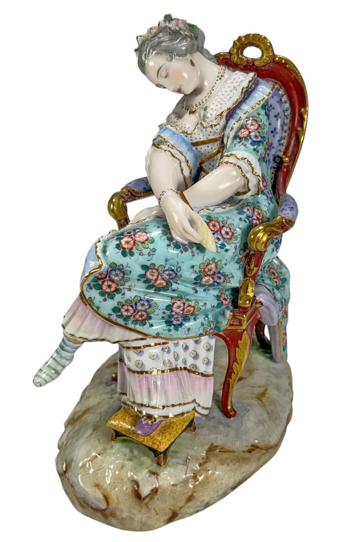 Meissen Seated Lady Porcelain Figurine: Meissen style porcelain figurine depicting an elegantly dressed seated lady asleep in an upholstered chair with a matching footstool. Finely hand-painted with floral decoration, gilt accents, and Roco