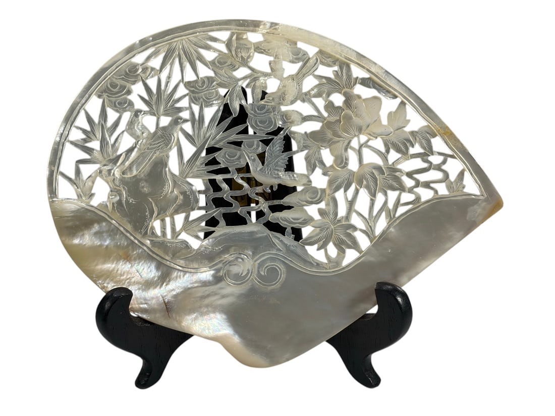 Chinese Carved Mother of Pearl Shell Plaque Displa: Finely carved mother-of-pearl shell plaque depicting birds among flowering plants and bamboo in an openwork design with scrolling wave motif. Includes a black folding wood display stand. Dimensions: 5